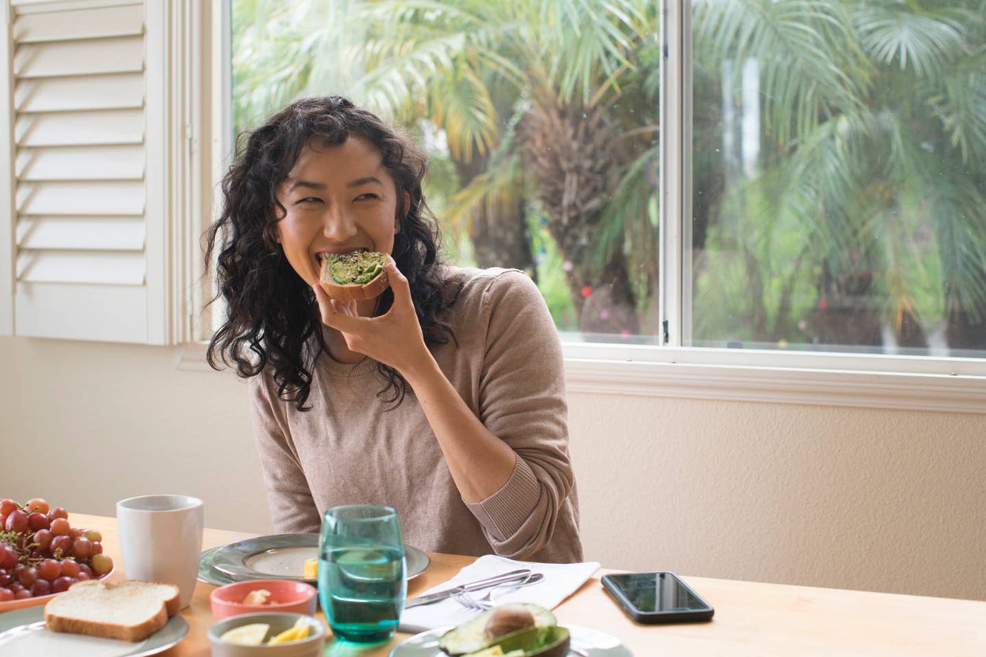Young woman eating avocado toast at home
