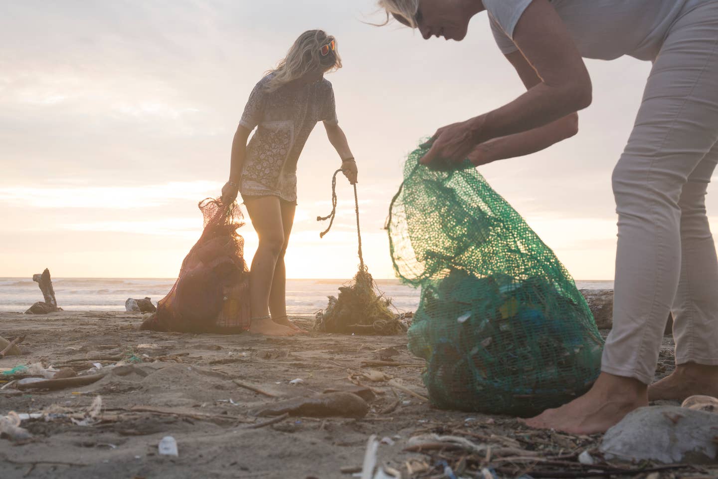 Mother and daughter collect garbage from beach